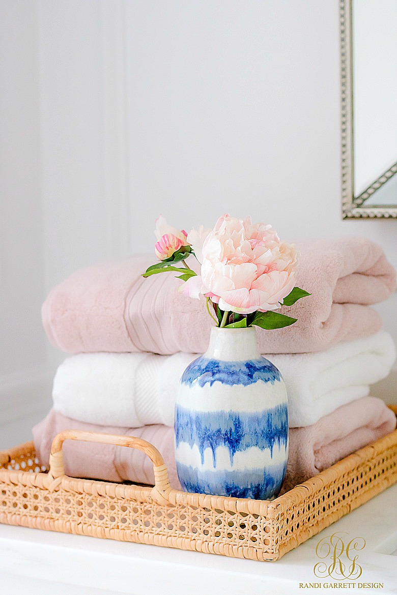 pink and white towels on wicker serving tray - glam bathroom