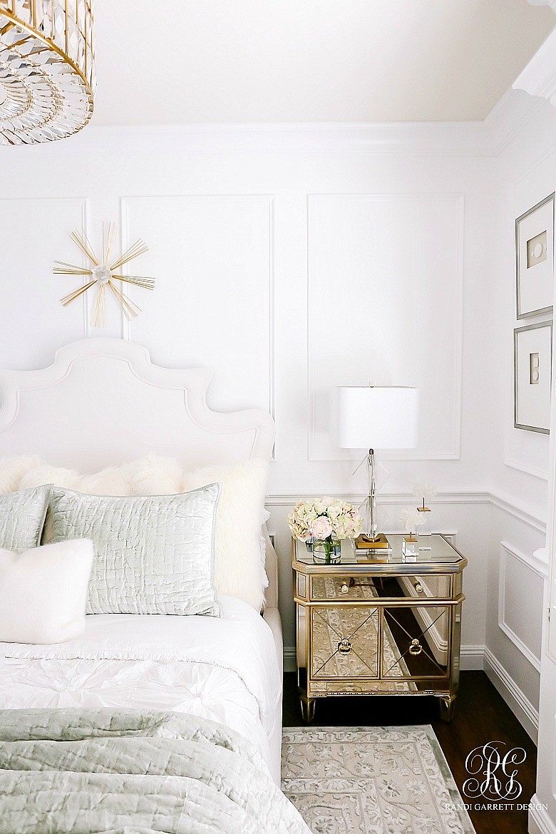 Luxe bedroom with mirrored nightstands and gold accessories and wainscoting 