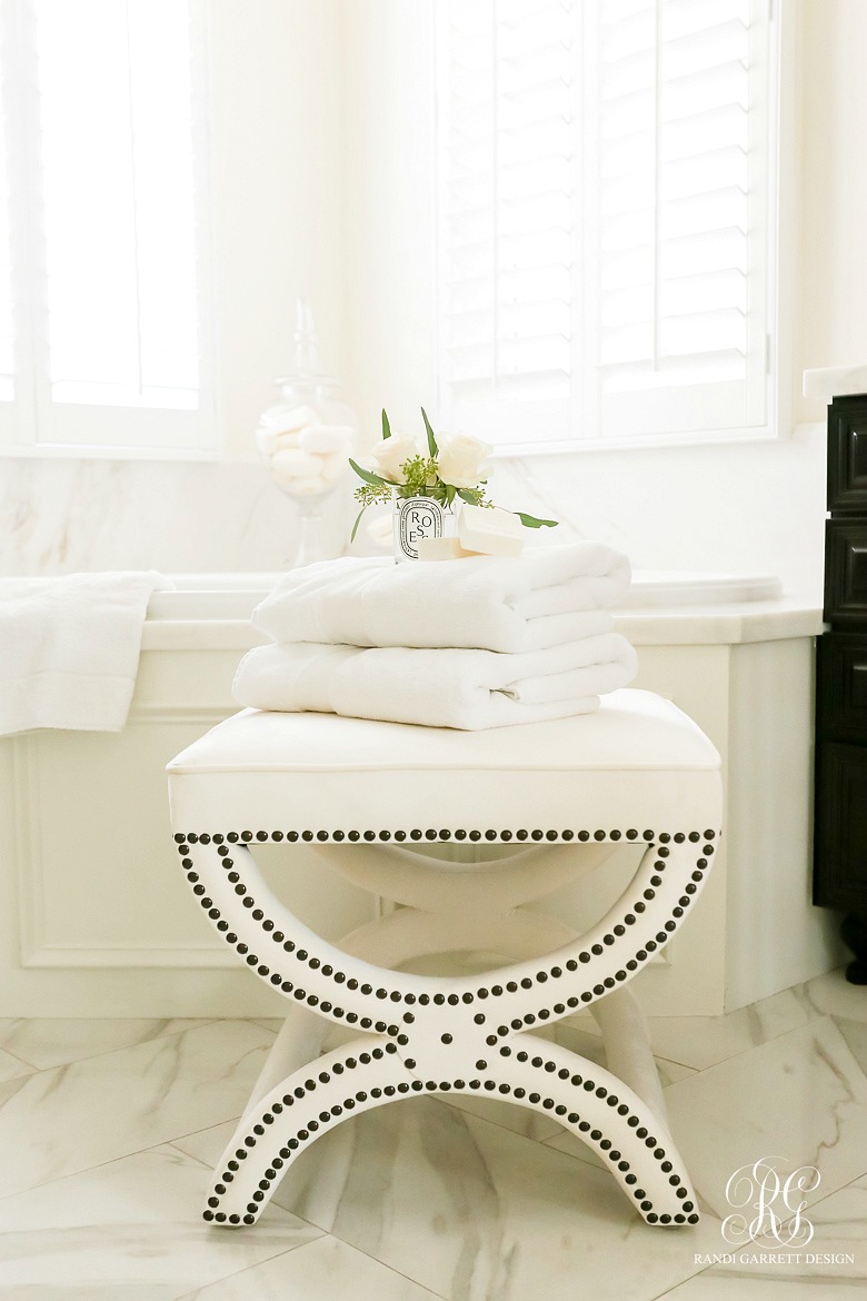 white velvet stool in white marble bathroom