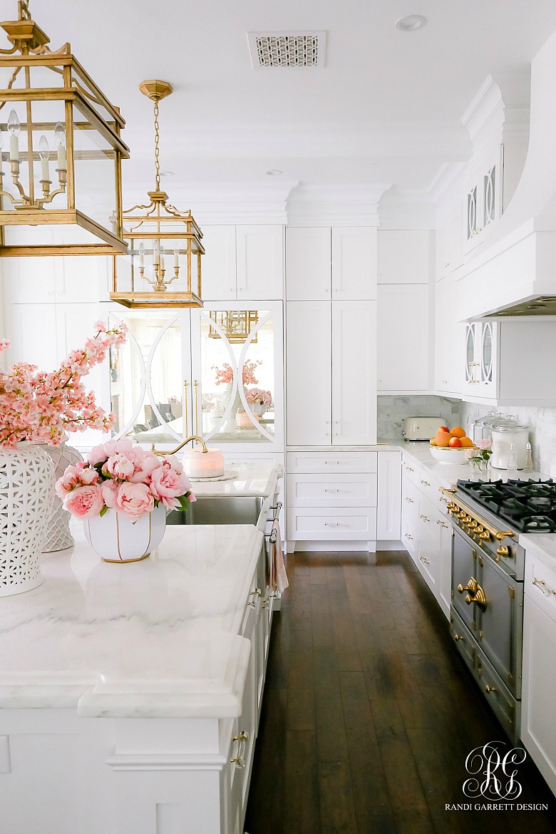 white glamorous kitchen -marble countertops - pink flowers - dark wood floors